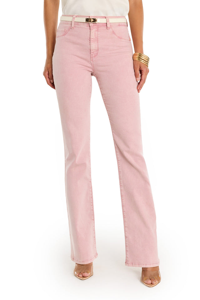 A woman stands against a white background, shown from shoulders to feet, wearing the Aria Flare Jean - Blush, a white top, gold bracelets, and open-toe nude heels.