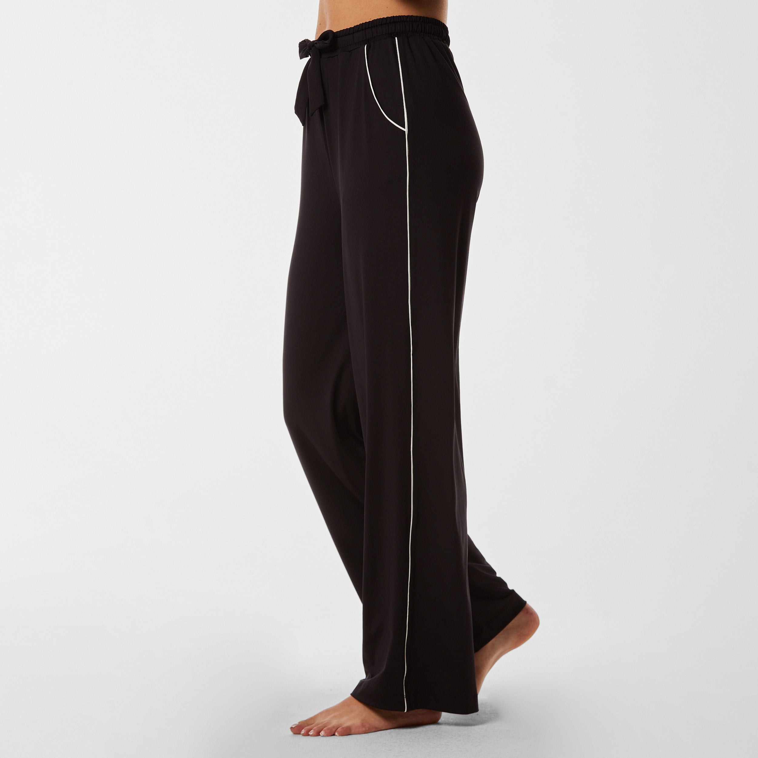 Side view of soft black pajama pants with white piping detail.