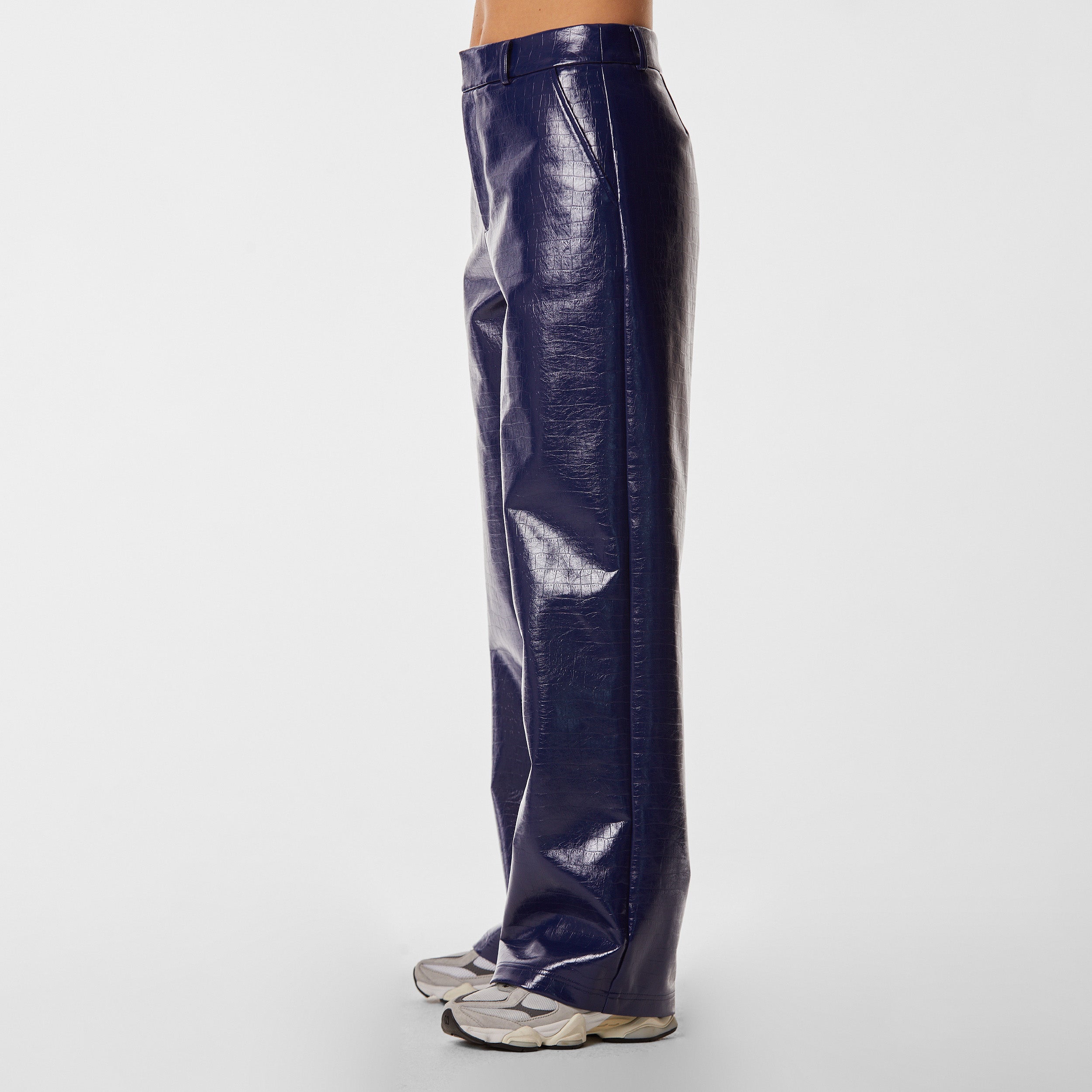Side view of woman wearing navy blue faux leather croco pattern embossed wide leg pant.