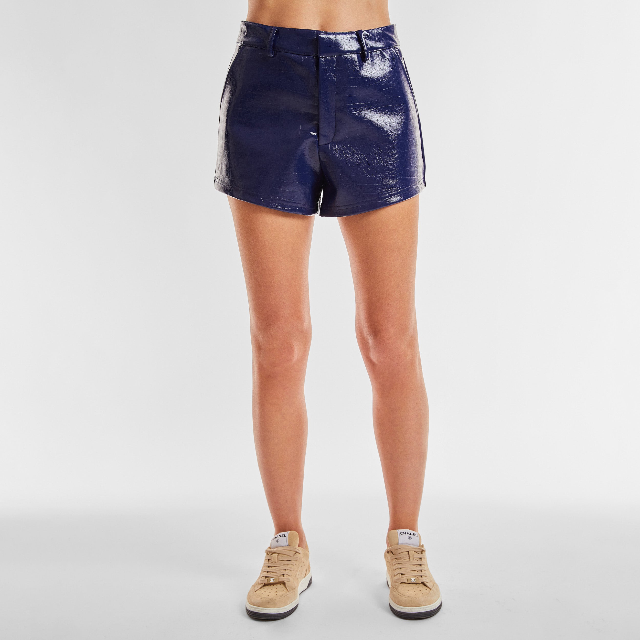 Front view of woman wearing blue faux leather short with croco embossed pattern.