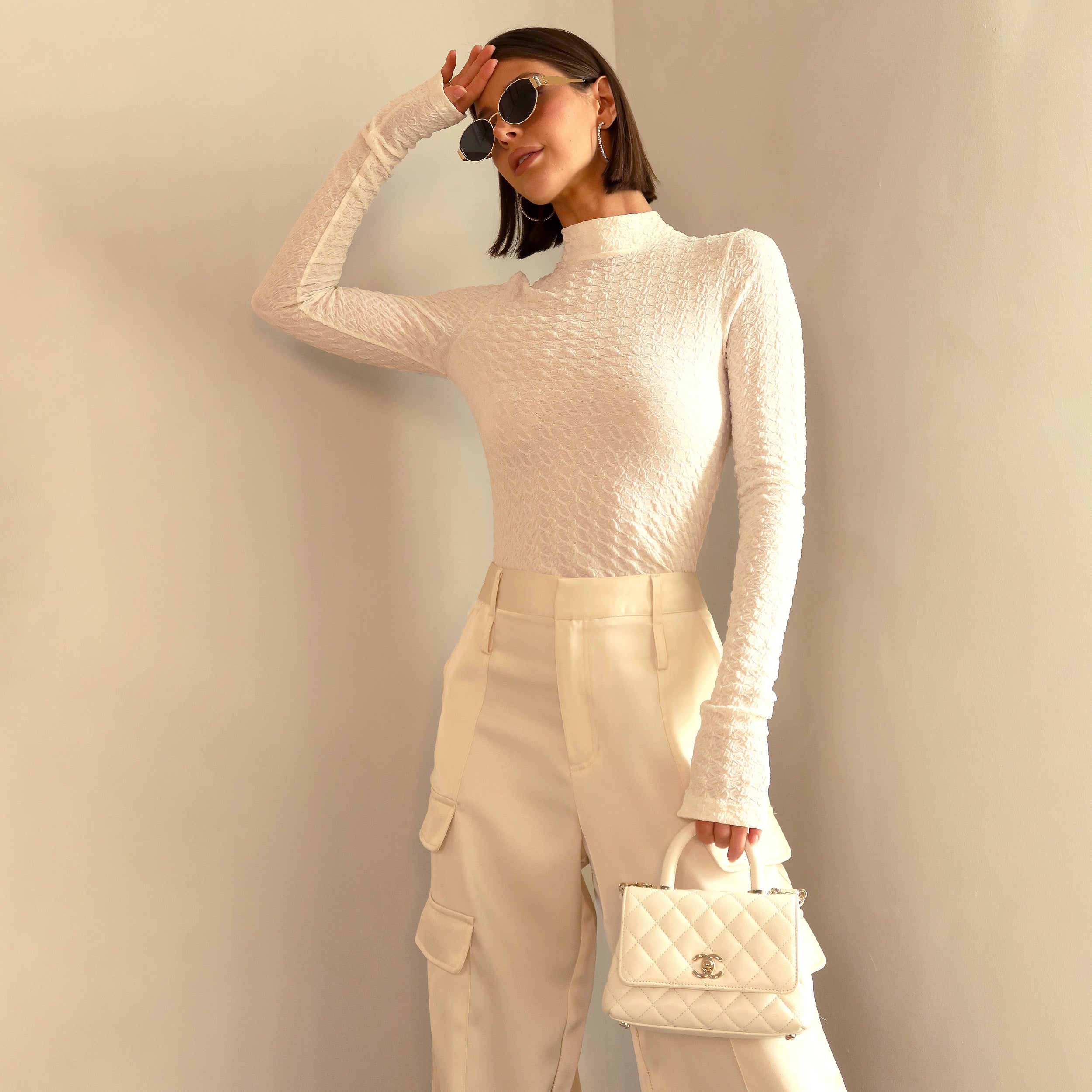 Woman wearing ivory stretch mesh textured turtleneck sweater