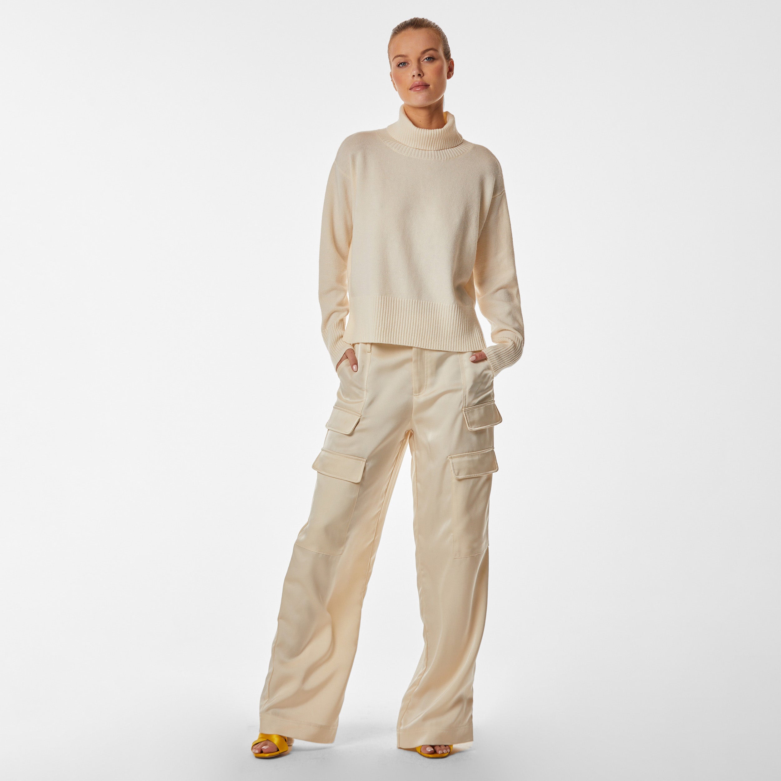 Woman wearing pearl colored oversized sweater and matching pearl satin cargo pant