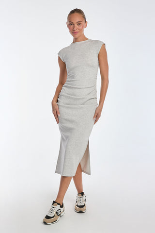 A person poses in the Daphne Dress - Heather Grey, a sleeveless, ultra-soft heathered modal dress with a bodycon fit and side slit. They pair it effortlessly with black and white sneakers, hair styled up against a plain white backdrop.