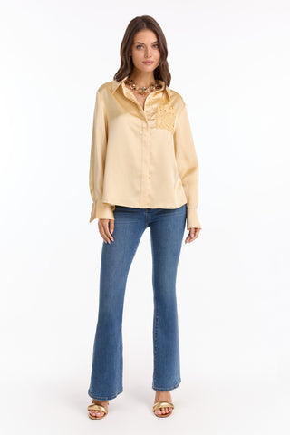 A woman faces forward against a white background, wearing the Amelia Silky Lace Blouse in Butter Yellow (Preorder), styled with blue flare jeans, gold sandals, and a chunky necklace.