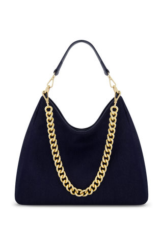 The Tribeca Chain Denim Bag - Indigo Denim features a luxe hobo design in dark indigo denim with a bold gold chain strap and black leather handle, shown on a plain white background.