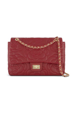 The Alessia Rose Embossed Leather Bag - Merlot is a red leather handbag with a rose-embossed pattern, featuring a gold chain strap and rectangular gold clasp on the front flap.