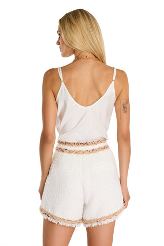 A woman with long blonde hair, wearing a white sleeveless top and Cheri Tweed Short in Pearl Multi, stands facing away against a white background.