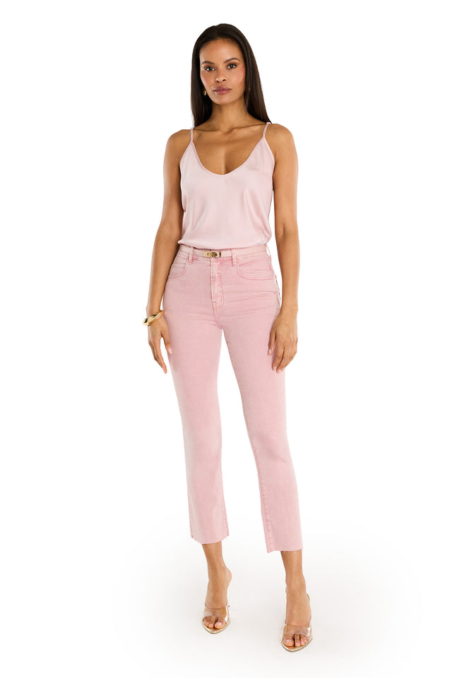 A woman stands facing forward against a white background, wearing a light pink sleeveless camisole, Nicolette Cropped Jean - Blush, clear heeled sandals, and a gold bracelet for an effortless summer look.