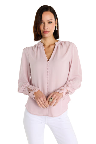 A woman with straight brown hair wears the Blake Lace Sleeve Blouse in blush and white pants, standing against a white background and looking at the camera with a neutral expression.
