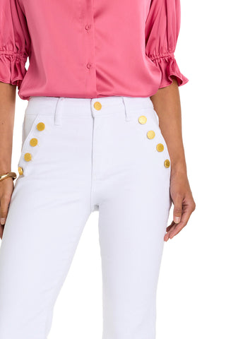 A person wearing a pink ruffled-sleeve blouse and the Allegra Bootcut Jean - White, which features high-waisted styling and gold detailing on the hips. Only the torso and upper legs are visible.