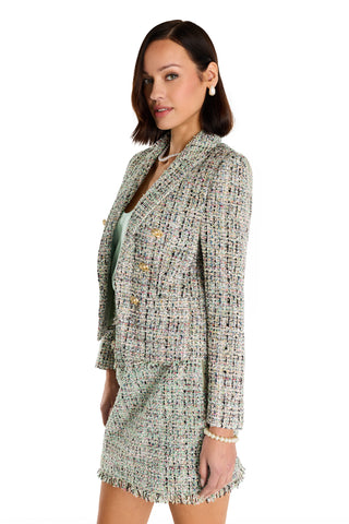 A woman with shoulder-length brown hair wears the Gabrielle Double Breasted Tweed Blazer in Teal Multi and pearl jewelry, posing sideways against a white background while looking at the camera.