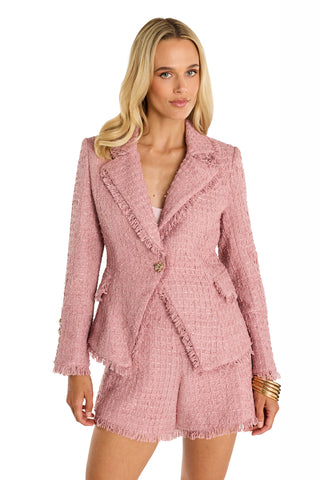 A woman with long blonde hair wears the Giselle Single Breasted Tweed Blazer in blush with matching shorts, featuring frayed edges, styled against a white background and accessorized with gold bangles.