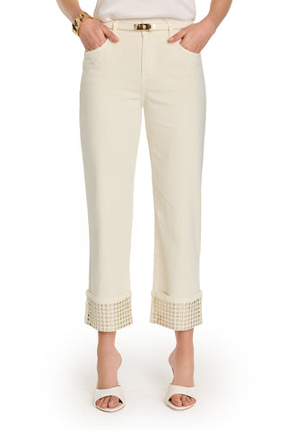 Wearing the Ren Cropped Cuff Jean - Gold Mirror, featuring cream color and wide, embellished cropped cuffs, paired with a slim belt, white heeled sandals, and a gold bracelet against a white background.