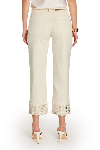 A woman shown from the back wears the Ren Cropped Cuff Jean - Gold Mirror, featuring off-white cropped wide legs with embellished hems, paired with white high-heeled sandals, a gold bracelet, and a white top.