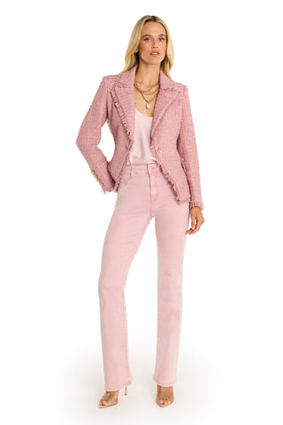A woman stands against a white background wearing the Giselle Single Breasted Tweed Blazer - Blush, a matching pink top, pink high-waisted jeans, nude heels, and layered gold necklaces.