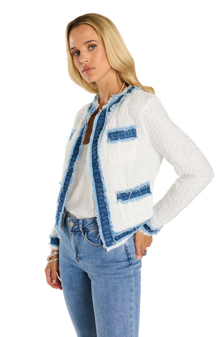 A woman with long blonde hair models the Julia Tweed Jacket - Denim/White over a white top and light blue jeans, standing with one hand in her pocket against a plain white background.