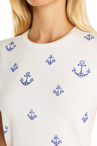 A close-up of a woman wearing the Amaya Ultra Soft T-Shirt - Crystal Anchors, featuring blue dotted anchor patterns. Only her lower face, upper torso, and partial blond hair are visible, highlighting the nautical-inspired design.