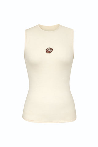 The Rosette Tank Top - Pearl is a sleeveless, cream-colored ribbed cotton top with a round neckline and a small rose applique on the chest.