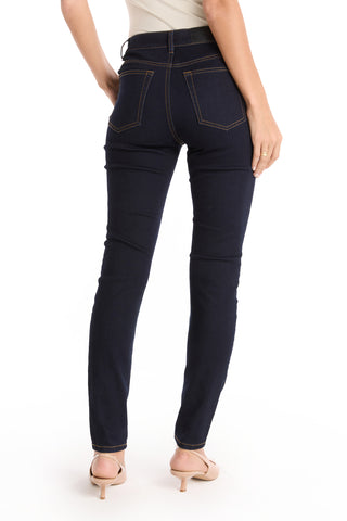 A person shown from the waist down, facing away, wears Layla Skinny Jean - Indigo with beige heeled sandals against a plain white background.