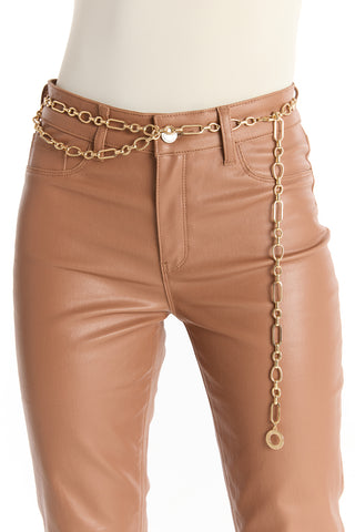 A mannequin wears high-waisted, tan leather pants paired with the Arden Chain Belt - Gold, a classic gold-finish accessory styled loosely at the side with a long decorative drop.
