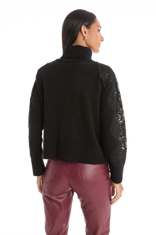 A woman with straight dark hair, wearing the Camille Lace Turtleneck Sweater in black and high-waisted maroon leather pants, stands facing away from the camera against a white background.