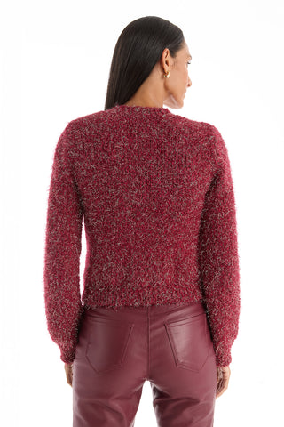A person with long, straight dark hair is seen from the back, wearing a Joana Knit Cardigan in Merlot and high-waisted maroon pants with visible back pockets, standing against a plain white background.