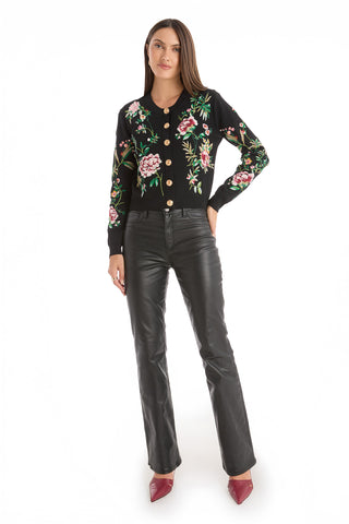 A woman stands facing forward against a plain white background, wearing the Alyssa Jacquard Cardigan - Black Floral, black leather pants, and burgundy heels.