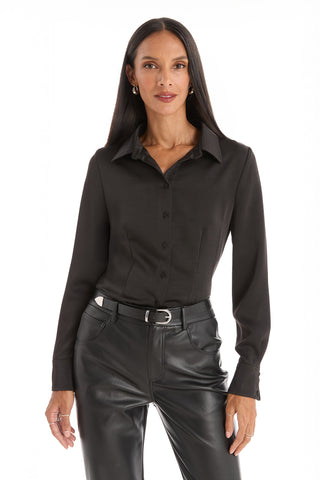 A woman with long dark hair models the Paulina Silk Blouse in black, paired with black leather pants, standing with one hand relaxed by her side against a plain white background.