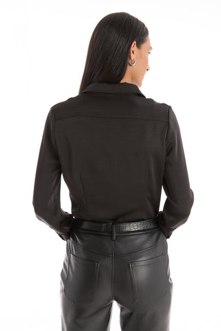 A woman with long, straight hair stands facing away, wearing the Paulina Silk Blouse in black and high-waisted black leather pants with her hands in her back pockets.