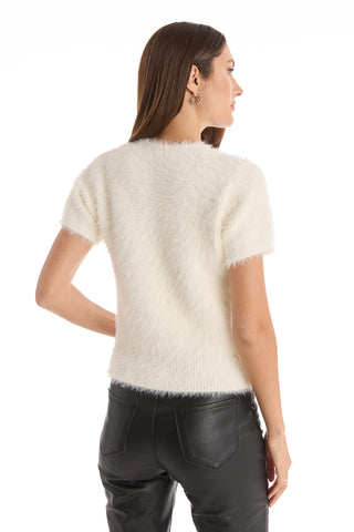 A woman with long brown hair, wearing the Angel Fluffy Sweater Top in white and black leather pants, stands with her back to the camera.