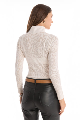 A woman with straight brown hair faces away from the camera in a slim-fitting Alina Rose Turtleneck Top - Pearl, featuring rose motif lace, paired with black leather pants against a white background.