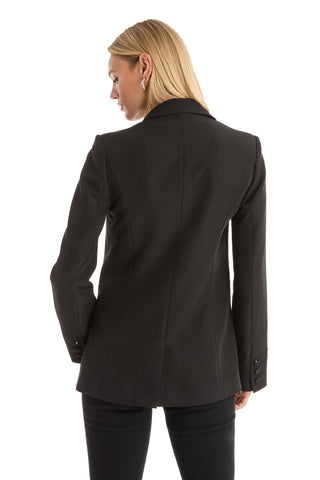 A woman with straight blonde hair wears the London Floral Sequin Blazer in black, paired with matching pants, standing with her back to the camera against a white background.