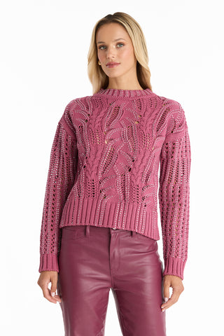 A woman wearing the Elea Crystal Knit Sweater in Sangria stands facing forward against a plain white background, paired with matching magenta leather pants.