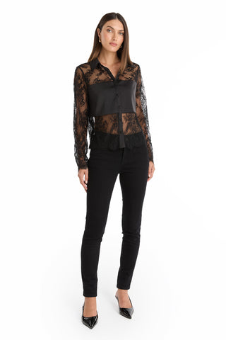 A woman stands against a white background wearing the Vienna Lace Blouse - Black, paired with black pants and pointed-toe heels. Her straight hair frames her face as she looks forward with a neutral expression.