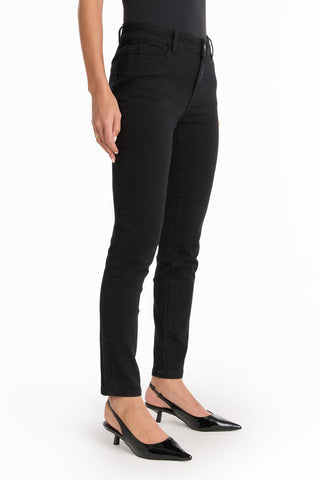 A model showcases the Layla Skinny Jean - Black with black pointed-toe heels, standing against a white background. Only the lower half of the body is visible.