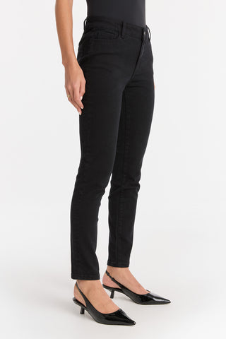 A person wearing the Layla Skinny Jean - Black stands against a plain white background, paired with a black top and black pointed-toe low-heel shoes. The image is cropped above the shoulders.