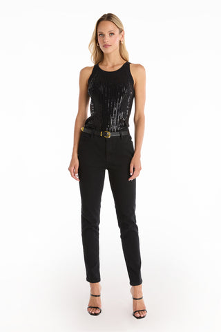 A woman faces forward against a white background, wearing the Shae Sequin Halter Tank in black, paired with black belted pants and black heeled sandals. Her hair is loose and she has a neutral expression.