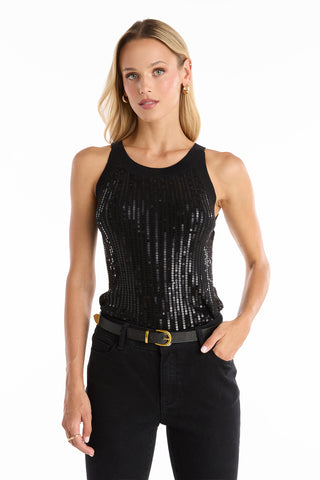 A woman with long blonde hair models the Shae Sequin Halter Tank in black, paired with black pants and a black belt. She stands facing forward, one hand in her pocket, against a plain white background.