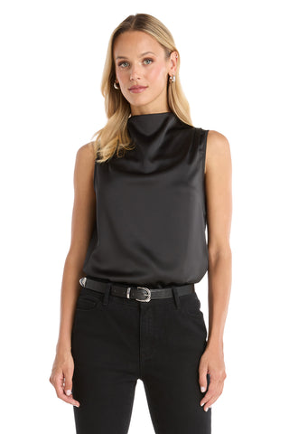 A woman with long blonde hair wears the Mara Silky Top - Black, styled with black jeans and a silver-buckled belt. She stands against a white background, looking at the camera with a neutral expression.