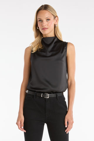 A woman with long blonde hair wears the Mara Silky Top in black, styled with black pants and a silver-buckled belt. She faces forward against a plain white background.