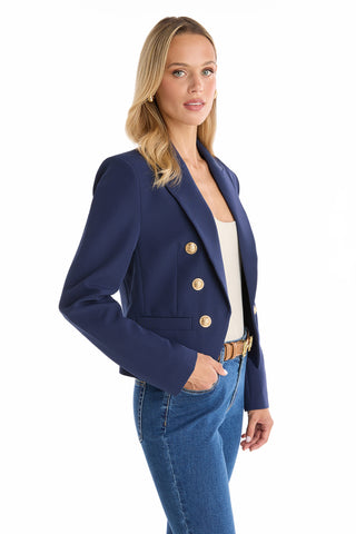 A woman with blonde hair wears the Gabrielle Double Breasted Blazer - Navy over a white top and blue jeans, standing against a white background.