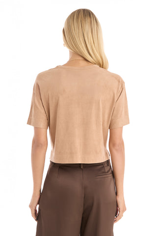 A woman with long blonde hair is shown from the back, wearing the Naya Suede T-Shirt - Cafe with a cropped fit and high-waisted brown pants against a plain white background.