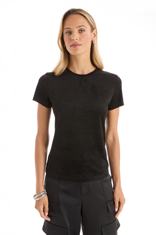 A woman with long blonde hair wears the Amaya Suede T-Shirt in black and black cargo pants, standing against a white background. She accessorizes with bracelets and small hoop earrings, her expression neutral.