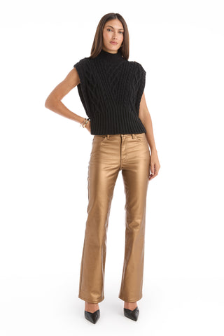 A woman faces forward in the Raina Cable Knit Button Sweater in black, paired with metallic gold pants and black pointed-toe heels against a white background.
