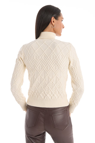 A woman with straight dark hair stands with her back to the camera against a white background, wearing the Cara Crystal Sweater in Pearl and dark brown leather pants.