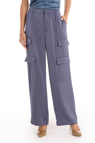 A person wears the Milan Satin Cargo Pant in navy—high-waisted, wide-leg cargo trousers with multiple large pockets—styled with tan pointed-toe heels and one hand casually in a pocket.