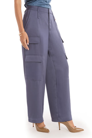 A person wears the Milan Satin Cargo Pant in navy—high-waisted, wide-leg trousers with large side pockets—paired with tan high-heeled shoes and a blue top. The satin-like pants stand out; image is cropped at the shoulders.