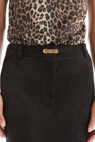 A person wears a leopard-print top tucked into the Kendra Sueded Midi Skirt - Black, featuring a high waist and gold clasp belt, with their hands relaxed at their sides.