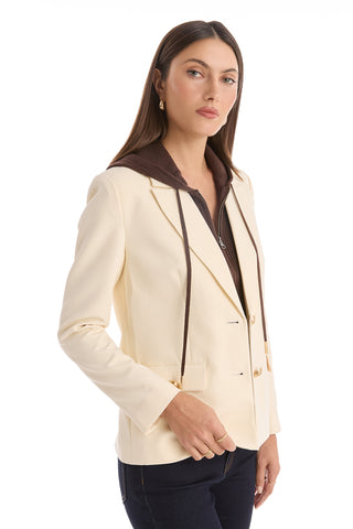 A woman with long straight brown hair confidently poses against a white background wearing the Kara Dickey Blazer - Pearl/Espresso over a brown zip-up top and dark jeans.