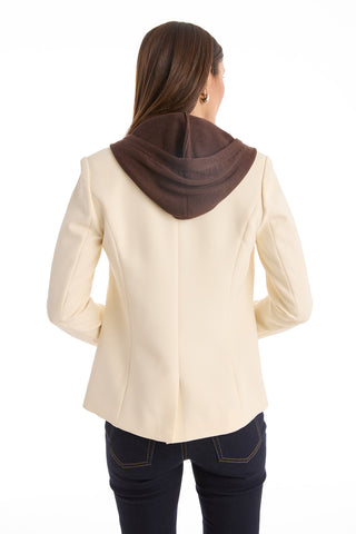 A woman with dark hair, dressed in dark jeans, faces away while wearing the Kara Dickey Blazer in Pearl/Espresso with a brown hood. The cream-colored suiting blazer features a detachable dickey and is set against a plain white background.
